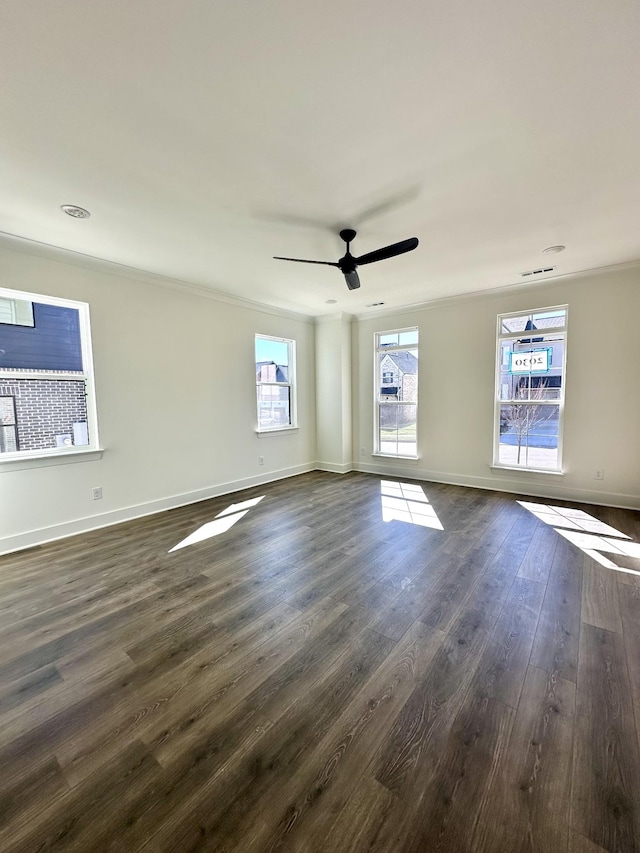 spare room featuring visible vents, baseboards, ceiling fan, ornamental molding, and dark wood-style flooring