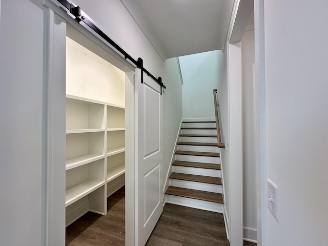 stairway featuring a barn door and wood finished floors