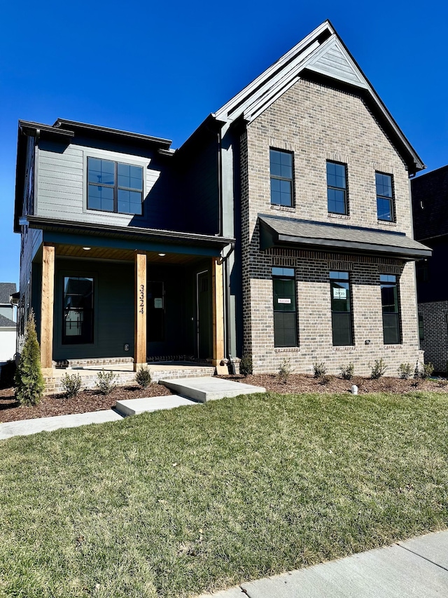 view of front of property featuring covered porch, brick siding, and a front lawn