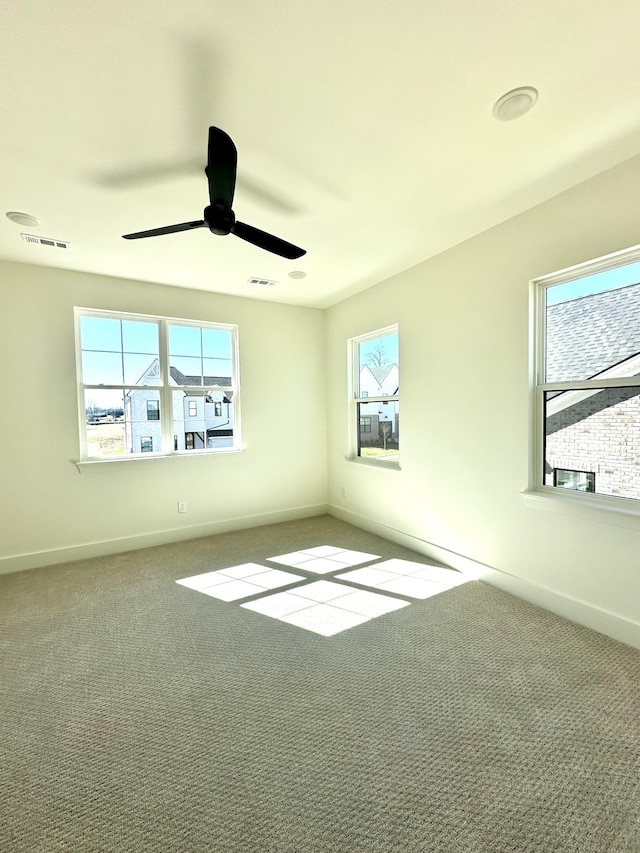 unfurnished room featuring carpet floors, visible vents, and baseboards