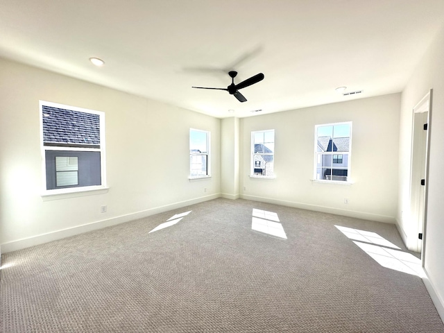 carpeted empty room with ceiling fan, visible vents, and baseboards