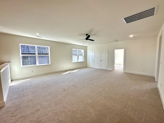 spare room with light carpet, baseboards, visible vents, and a ceiling fan