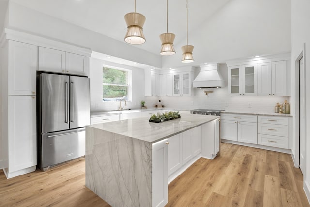 kitchen featuring white cabinets, a center island, stainless steel appliances, and custom exhaust hood