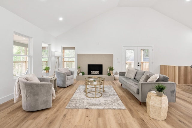 living room featuring a healthy amount of sunlight, french doors, high vaulted ceiling, and light hardwood / wood-style flooring