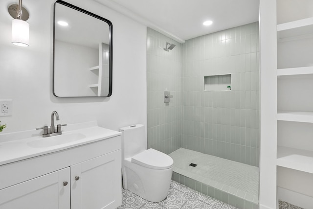 bathroom featuring tiled shower, tile patterned floors, vanity, and toilet