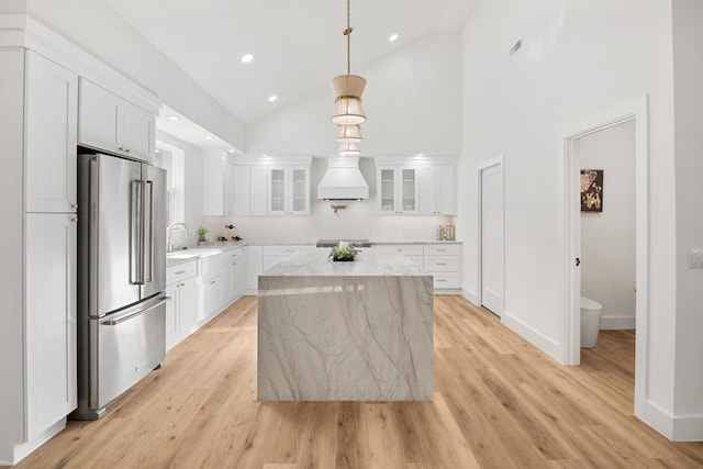 kitchen featuring a center island, white cabinets, stainless steel appliances, and high vaulted ceiling