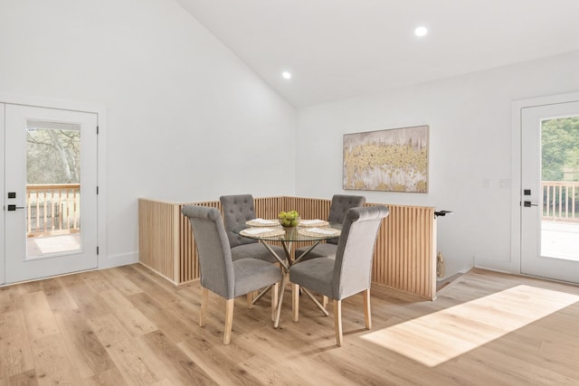 dining room with high vaulted ceiling and light wood-type flooring