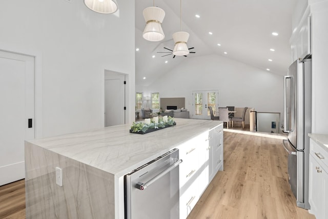 kitchen with white cabinetry, hanging light fixtures, light hardwood / wood-style floors, a kitchen island, and appliances with stainless steel finishes