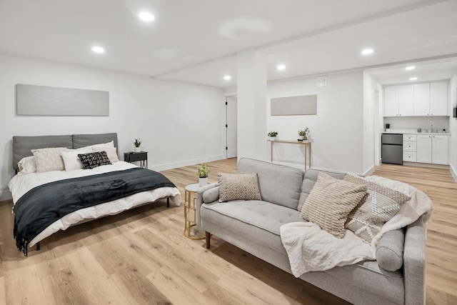 bedroom with light wood-type flooring and black fridge