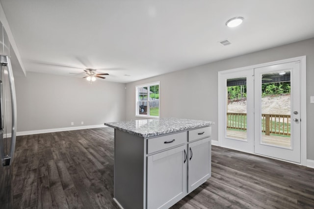 kitchen featuring light stone countertops, white cabinets, a center island, and a healthy amount of sunlight