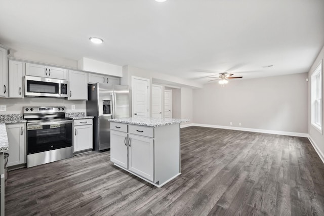 kitchen with light stone counters, a center island, dark hardwood / wood-style floors, and stainless steel appliances