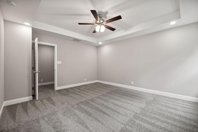 empty room featuring ceiling fan, carpet flooring, and a tray ceiling