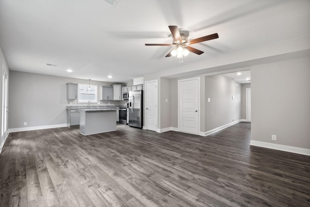 unfurnished living room featuring ceiling fan and dark wood-type flooring