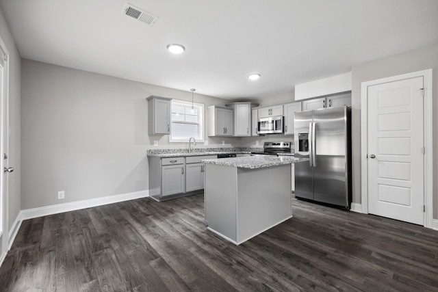 kitchen featuring pendant lighting, appliances with stainless steel finishes, a center island, dark hardwood / wood-style flooring, and gray cabinets