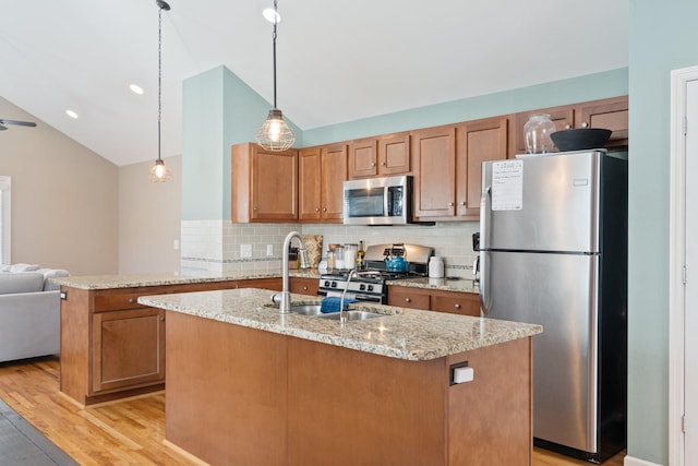 kitchen featuring kitchen peninsula, light wood-type flooring, stainless steel appliances, vaulted ceiling, and pendant lighting