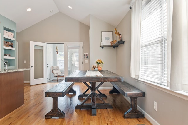 dining space featuring french doors, light hardwood / wood-style floors, vaulted ceiling, and a wealth of natural light