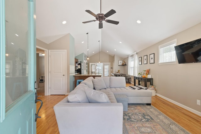 living room with ceiling fan, light hardwood / wood-style flooring, and lofted ceiling