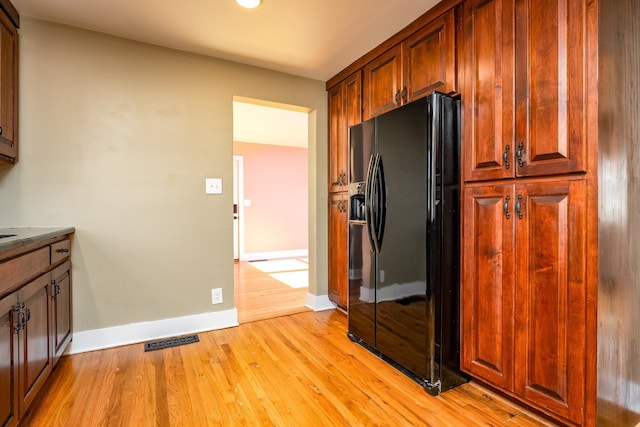 kitchen featuring light hardwood / wood-style flooring and black fridge