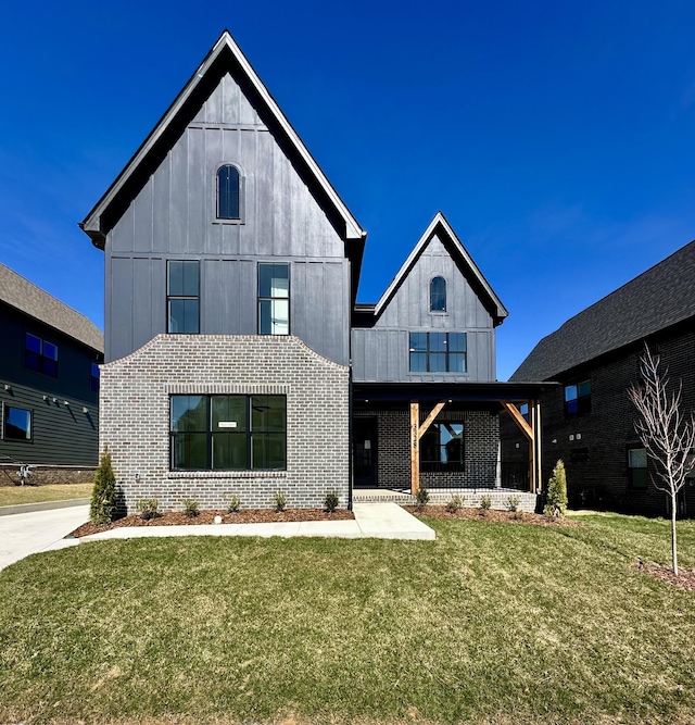 modern farmhouse style home with brick siding, a front lawn, and board and batten siding