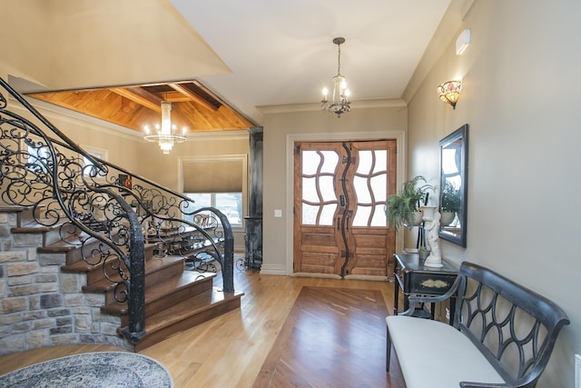 entrance foyer with ornamental molding, light wood-type flooring, and an inviting chandelier