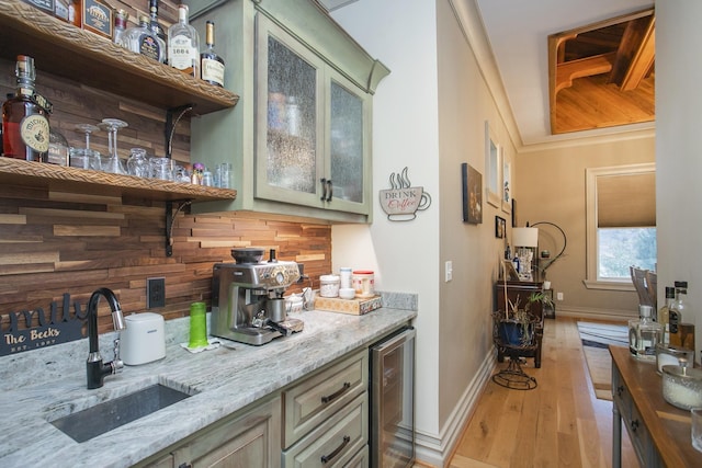 bar with wine cooler, light stone countertops, sink, and light wood-type flooring