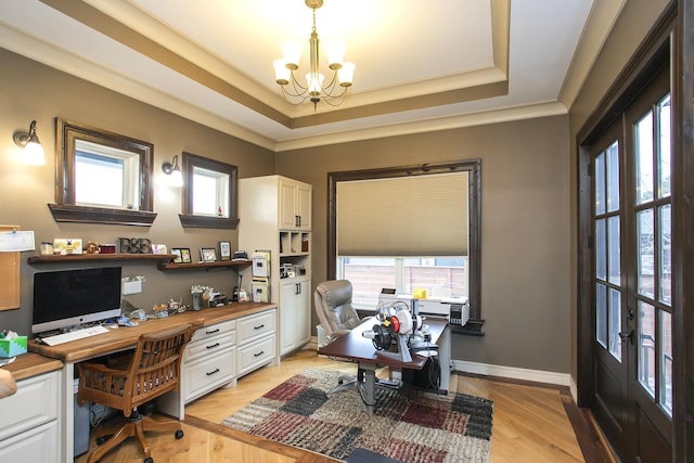 office space featuring a notable chandelier, a tray ceiling, light hardwood / wood-style flooring, and plenty of natural light