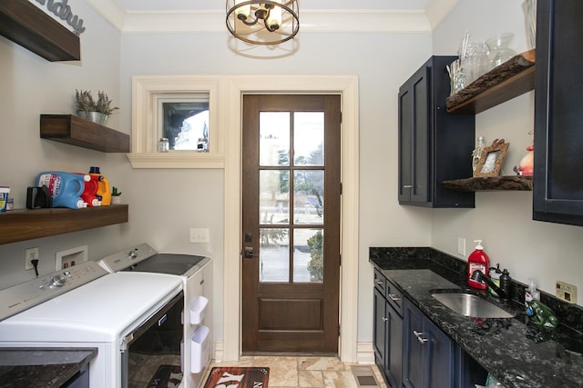 clothes washing area featuring crown molding, cabinets, washer and clothes dryer, and sink