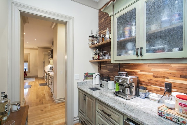 bar with crown molding, sink, light stone counters, and light hardwood / wood-style flooring