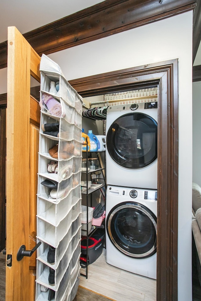 laundry room with hardwood / wood-style flooring and stacked washing maching and dryer