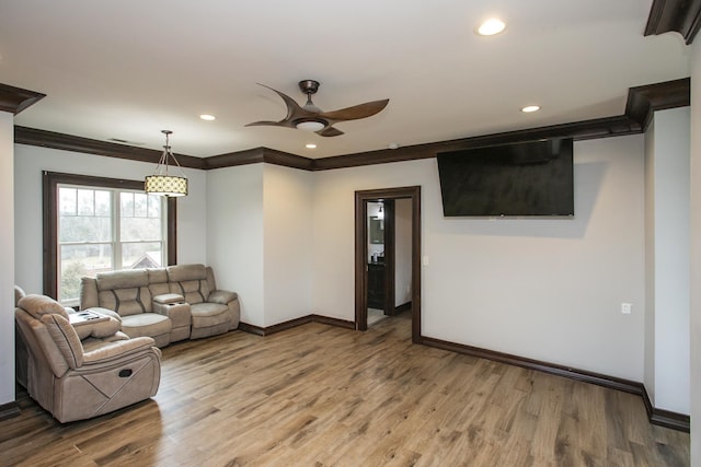 living room with ornamental molding, wood-type flooring, and ceiling fan