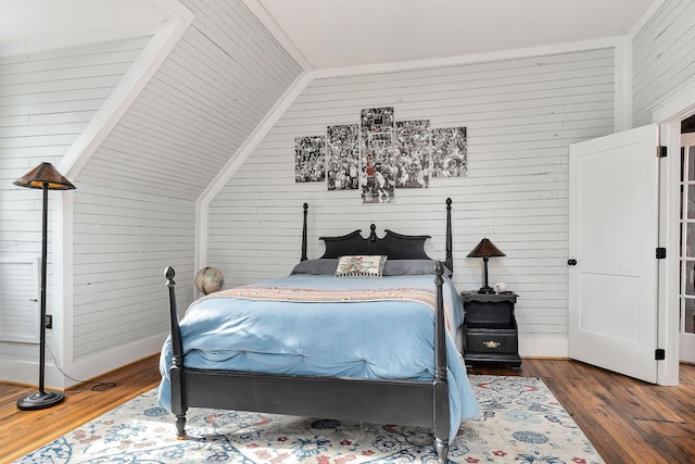 bedroom featuring wooden walls, dark hardwood / wood-style floors, and vaulted ceiling