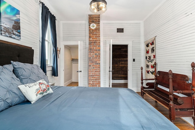 bedroom with wood walls and wood-type flooring