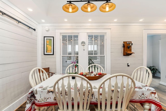 dining area with wooden walls and hardwood / wood-style flooring