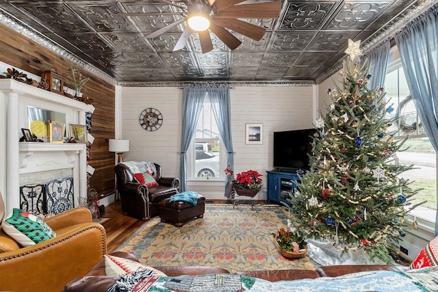 living room with wood-type flooring, ceiling fan, and wood walls