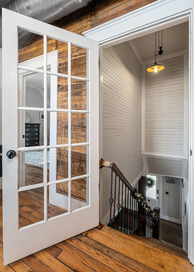 staircase with hardwood / wood-style floors, crown molding, and wooden walls