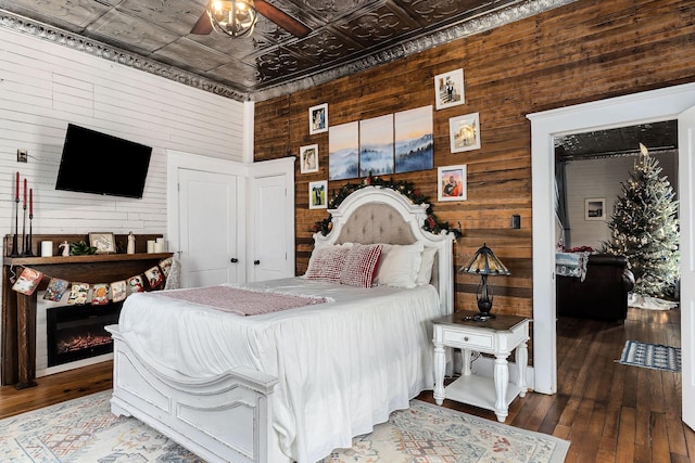 bedroom featuring wood walls, hardwood / wood-style floors, and ceiling fan