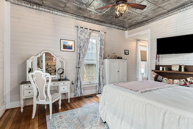 bedroom featuring dark hardwood / wood-style floors, ceiling fan, and wood walls