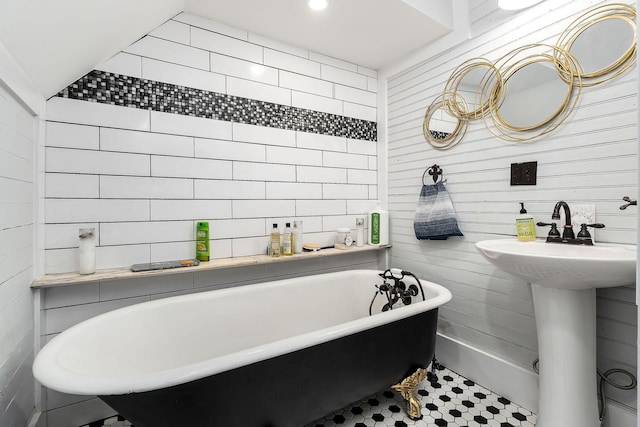 bathroom with a tub to relax in, wood walls, and sink