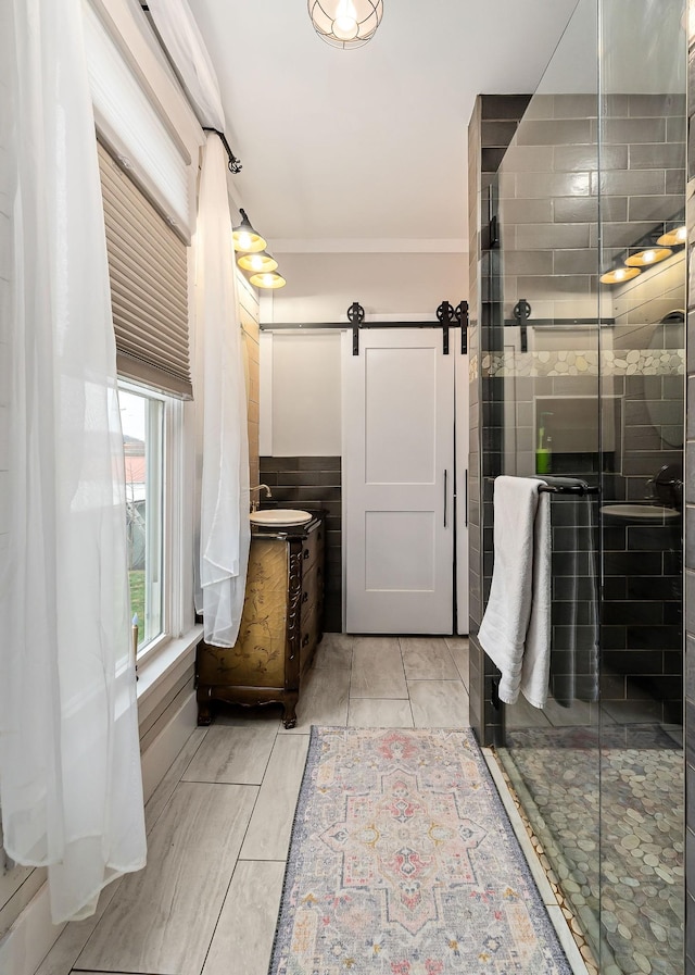 bathroom featuring walk in shower, tile patterned floors, crown molding, vanity, and tile walls