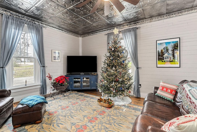 living room featuring wood-type flooring, ceiling fan, a healthy amount of sunlight, and wood walls