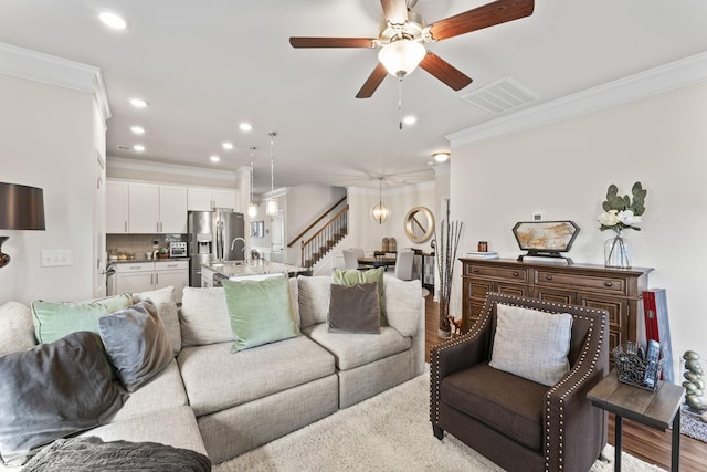 living room featuring light hardwood / wood-style flooring, ceiling fan, and crown molding