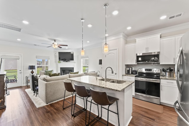 kitchen featuring sink, light stone counters, dark hardwood / wood-style flooring, white cabinets, and appliances with stainless steel finishes