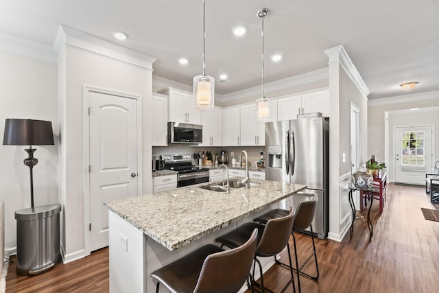 kitchen featuring white cabinets, dark wood-type flooring, stainless steel appliances, and an island with sink