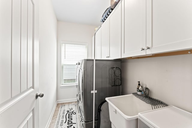 laundry area with washer and clothes dryer, cabinets, and light hardwood / wood-style flooring