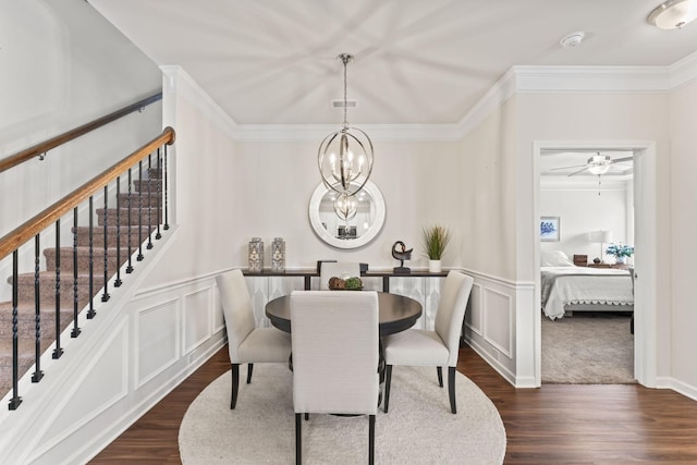 dining room with ceiling fan with notable chandelier, ornamental molding, and dark wood-type flooring