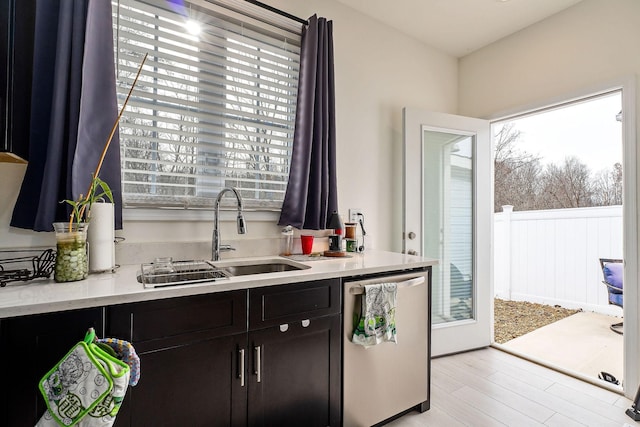 kitchen featuring dishwasher, dark brown cabinets, light hardwood / wood-style floors, and sink