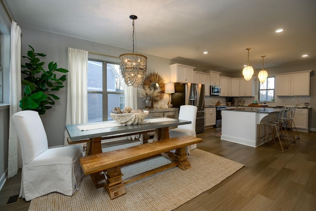 dining area with dark wood-type flooring and an inviting chandelier