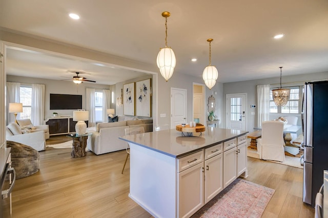 kitchen with a center island, stainless steel refrigerator, plenty of natural light, and white cabinets