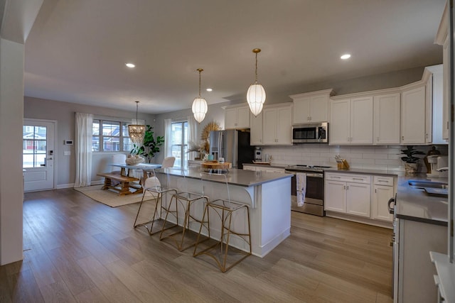 kitchen featuring white cabinets, a wealth of natural light, a kitchen island, and stainless steel appliances