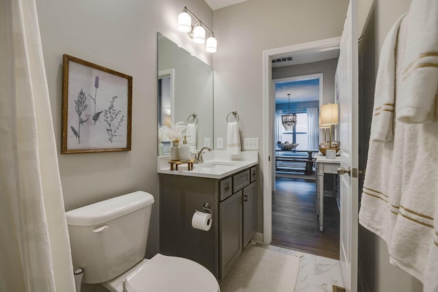 bathroom featuring a chandelier, vanity, wood-type flooring, and toilet